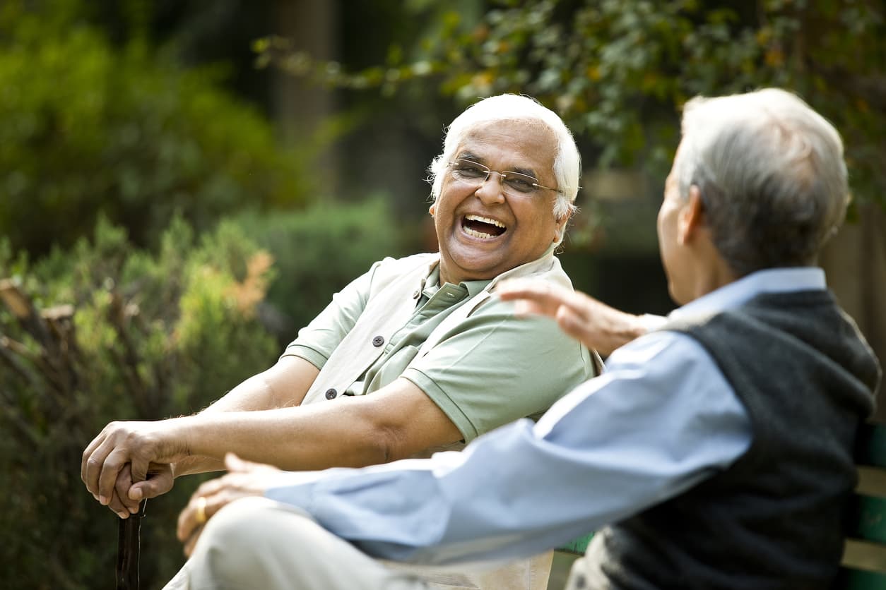 Two men sitting in a garden laughing with each other