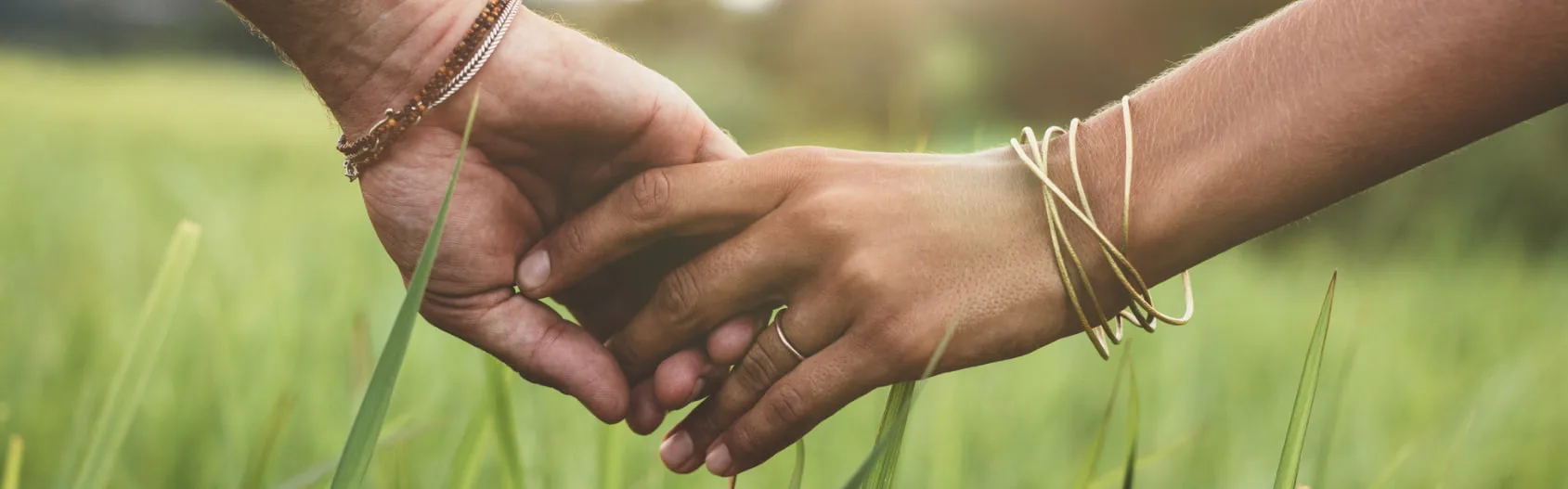 Can you be addicted to a person? - an image close up of two people holding hands with green nature scenery in the background
