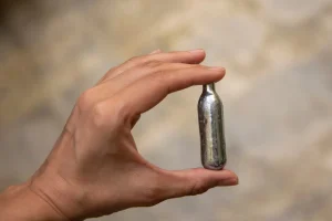What Does Nitrous Oxide Do? A hand holding a small vial of nitrous oxide