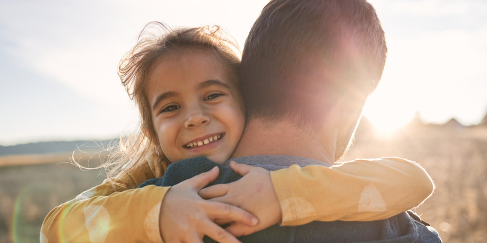 little girl hugging her parent in the sun
